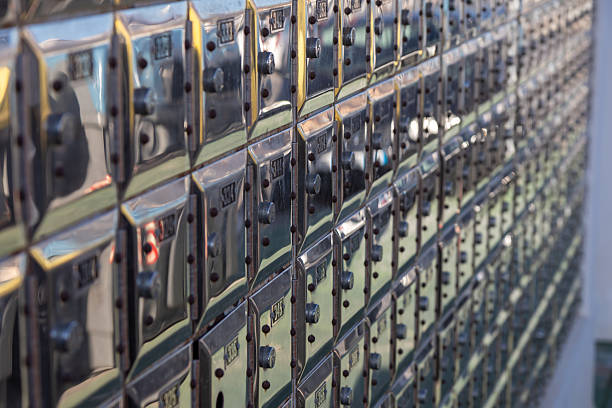 A full wall of gleaming, metallic post office boxes featuring individual locks and numbering. Reflective surfaces in an indoor mail room setting. Ideal for security concepts