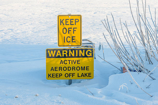Keep Off Ice Sign at Winter Airfield Anchorage, Alaska. Aviation safety sign marking an active aerodrome on a snow-covered frozen lake.