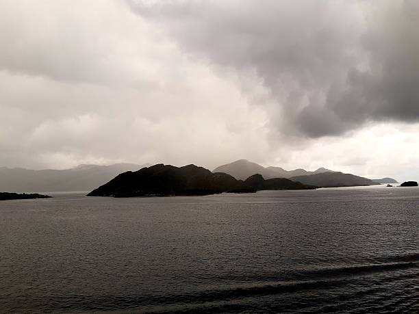 Small, dark, rocky islands stand out against the silvery, reflecting water of the North Sea under a heavy, dramatic sky.