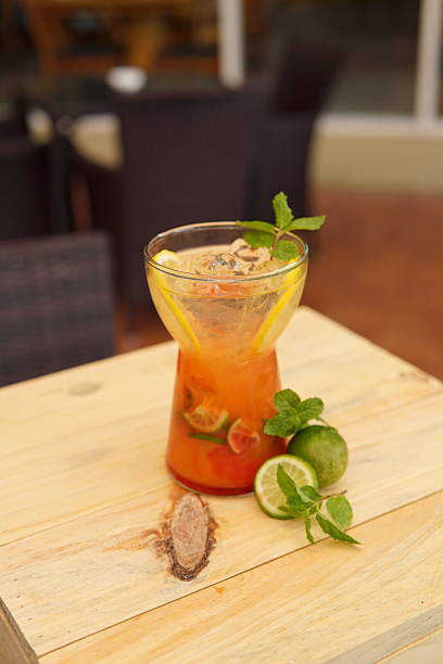 Refreshing Orange Drink with Lime and Mint on a Light Wooden Table