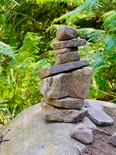 A Stone Cairn in focus. In the background the distant Whisky Falls, taken in the Nelson Lakes National Park, New Zealand.