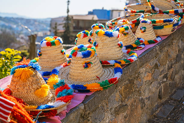 Vibrant straw hats with rainbow tassels line a sunlit stone wall in Chefchaouen, Morocco. A lively, handmade market feel with bright colors and Mediterranean charm. Perfect for travel, culture, and craft themes.