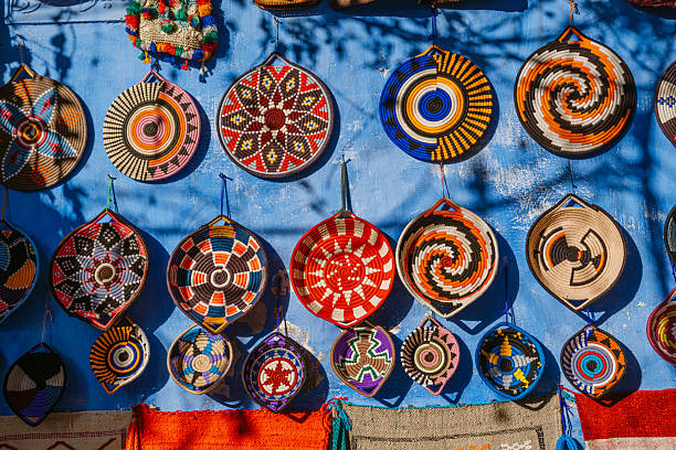 Vibrant, round woven baskets hang against a vivid blue wall in Chefchaouen, Morocco. A traditional market display showcasing color, texture, and the rich craft of Moroccan artisans.