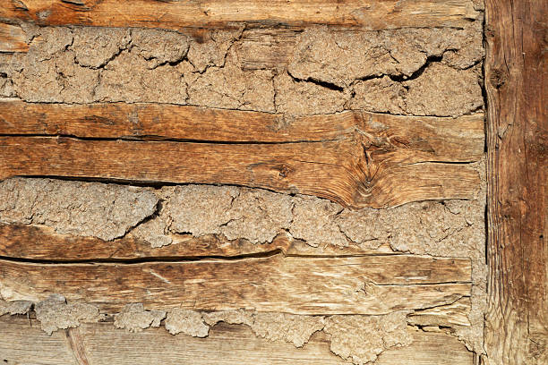 Close-up detail of traditional wooden wall constructed with horizontal timber beams and natural clay infill. Rustic architecture element showing old building techniques, natural materials, and handcrafted construction. Ideal as texture or background.