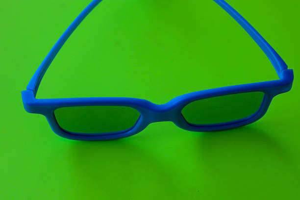 Bright blue glasses with dark lenses are placed on a rich green background, creating a dynamic color contrast. This minimalist accessory composition,