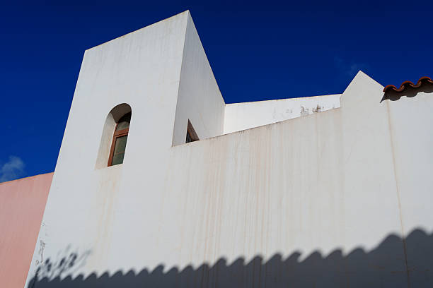 Clean geometric walls and strong shadow pattern create a minimalist exterior architectural scene.