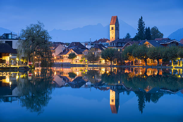 Interlaken, Switzerland townscape on the Aare River at blue hour with river reflections.