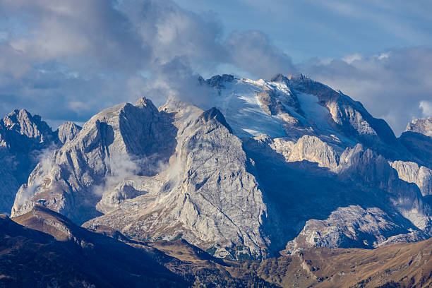 Dolomites mountain landscape under cloudy and stormy weather with low visibility, mist, and dramatic limestone peaks. Alpine environment showing changing climate conditions, rugged geology, moody sky, high altitude terrain, European Alps scenery, and atmospheric mountain background