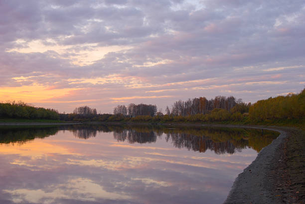 Bright purple sunset the river in the water reflects the clouds and trees a quiet autumn evening.