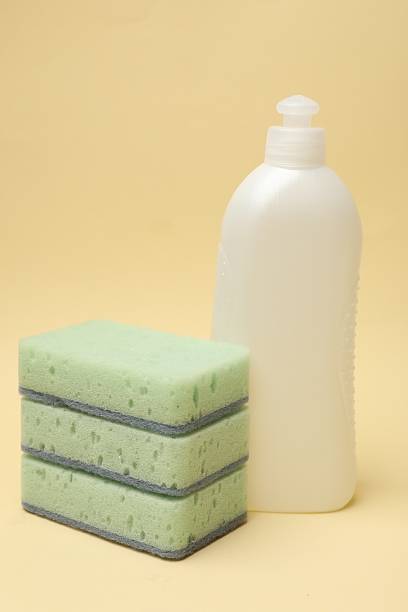 Kitchen sponges and dish soap on beige background, closeup