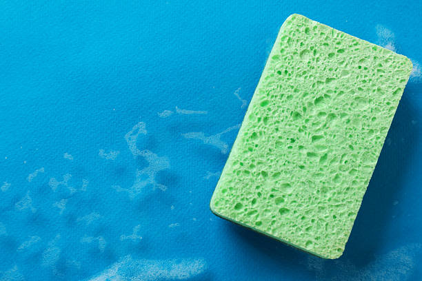 Kitchen sponge and foam on light blue background, top view. Space for text