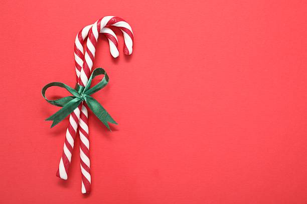 Christmas treat. Tied candy canes on red background, top view. Space for text
