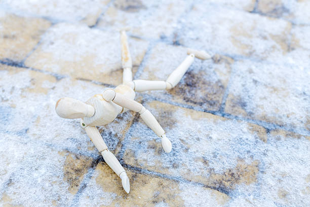 There is a white figure lying on the ground. It's a mannequin, and it's in distress. ice on the footpath, danger of falling
