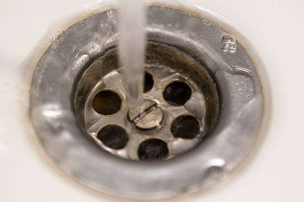 Close up view of running water flowing into a metal sink drain, showing household plumbing, water usage and everyday domestic maintenance.