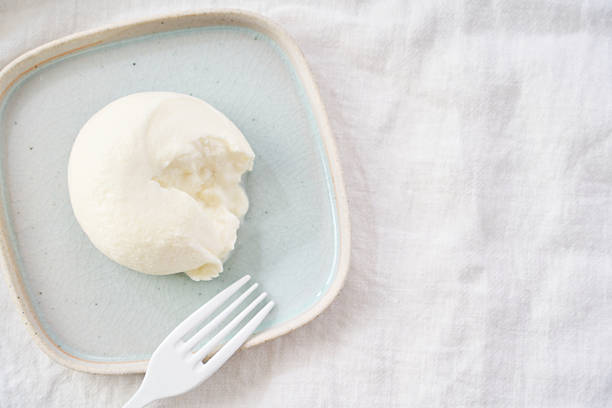 Burrata cheese cut open with creamy stracciatella filling, photographed as a simple bright ingredient shot on a plate—ideal for Italian food, menu, recipe, and dairy concepts.