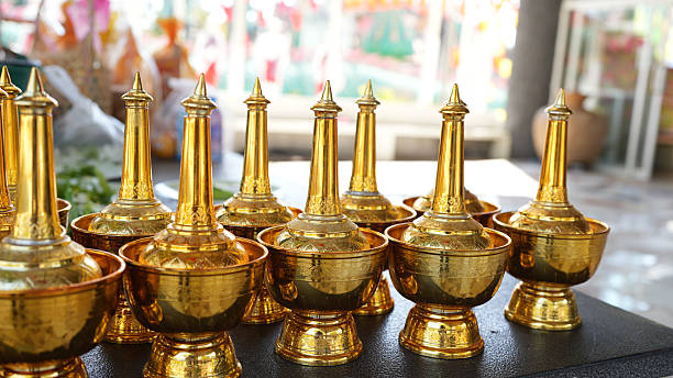 Golden decorative bowls with pointed lids arranged in row, showcasing intricate craftsmanship and vibrant colors in background
