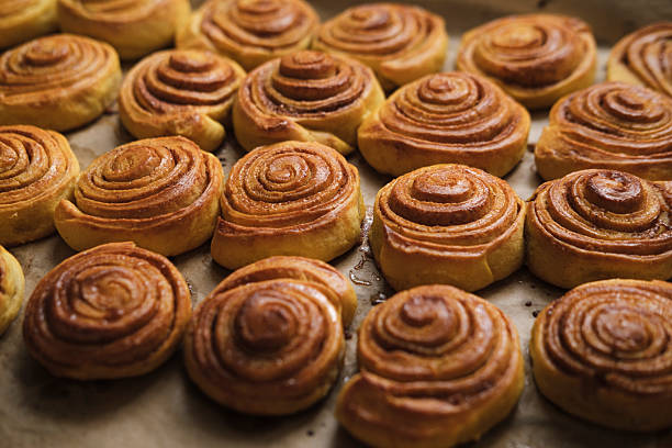 baked crispy cinnamon rolls right from oven on tray , fresh homemade pastry