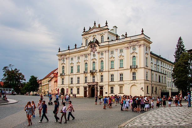 Prague, Czech Republic. August 21st, 2009: Tourists walking and gathering on a historic cobblestone square in front of an ornate palace building in the center of Prague. Lively urban scene reflecting tourism, cultural heritage, and everyday city life in the Czech capital. Editorial use only.