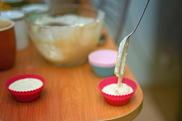Filling silicone molds with cottage cheese batter using a metal spoon to make syrniki. Traditional Eastern European cooking.