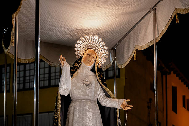 Decorated virgin mary statue with silver halo and sacred heart, illuminated and carried in a solemn semana santa night procession, rich in tradition and devotion