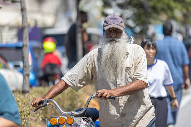31 January 2026, George Town - Penang.An elderly Indian man walks with his bicycle through the Thaipusam festival grounds.