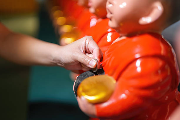 Action of a Buddhists is insert the coin in the alms bowl to make a merit at temple. Close-up with selective focus.