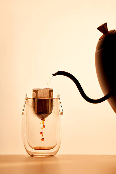 Minimalist brewing process of drip coffee in a glass mug with a gooseneck kettle