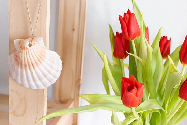 Fresh red tulips arranged indoors, photographed in soft natural light with shallow depth of field. Elegant spring flowers conveying freshness, simplicity, and calm interior atmosphere.