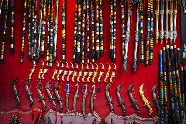Vibrant market display of traditional swords, daggers, and ornate handles against a bold red backdrop at Pushkar’s famed fair, showcasing Indian craftsmanship, color, and cultural heritage.