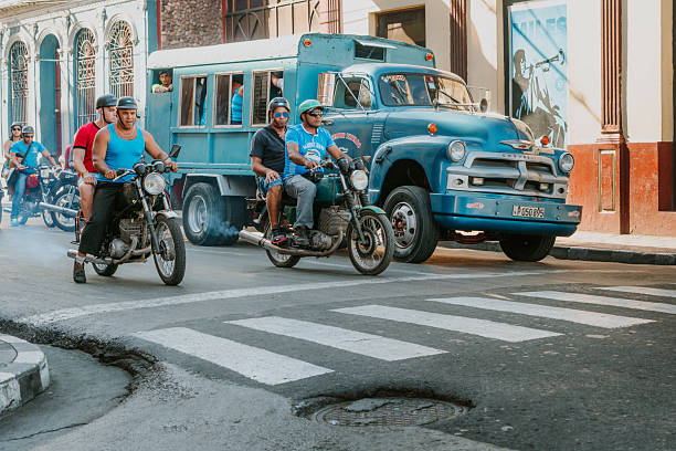 santiago de cuba, Cuba – January 23, 2025: The two men riding a vintage red motorcycle with a sidecar through a sunny city street, evoking nostalgia and classic automotive charm.