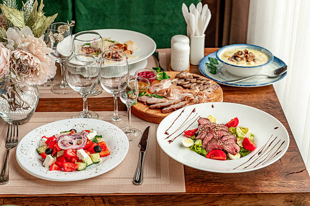 Delicious meals served on a wooden table during a dining experience. Various dishes are arranged on a wooden table with glasses and cutlery for a meal setup at a dining location.