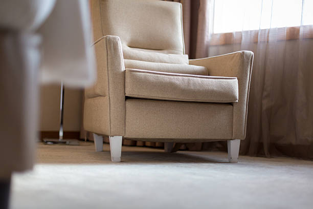 A calm and inviting hotel room interior featuring a comfortable armchair placed near a window with sheer curtains. Warm natural light fills the space, creating a cozy, home-like atmosphere ideal for relaxation, travel stays, or lifestyle concepts.