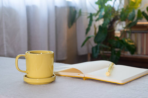 istock Hot black coffee in a yellow ceramic mug on the table with a notebook and pen. 2259255456
