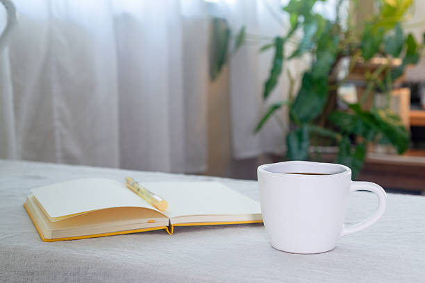 istock Hot black coffee in a white ceramic mug on the table with a notebook and pen. 2259255464