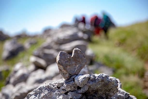A close up shot of a heart shaped stone, placed on an old stone wall, known as \