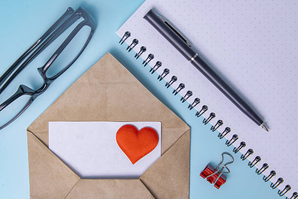 An empty page in a notebook, red hearts, a pen and glasses