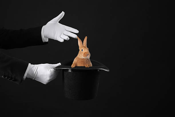 istock Magician showing trick with top hat and rabbit on black background, closeup. Space for text 2259277142