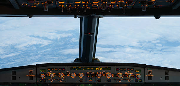 Airplane cockpit with illuminated controls flying high above a cloudy sky