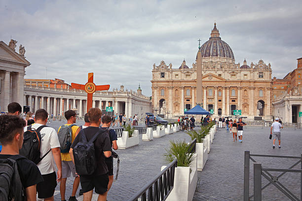 Closeup of wooden Italian cross Catholic rosary with Assisi text and bokeh blurry background of Vatican church St Peter's Square Basilica during mass audience
