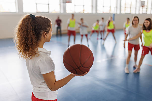istock School girl holding basketball training with classmates. 2259286326