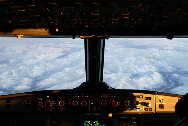Cockpit view from an airbus a320 flying over snow-covered mountains at sunrise