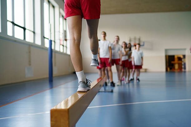 Students learning balance and coordination in a school gym during physical education.