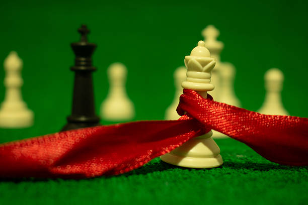 two translucent glass/acrylic chess pieces (queen and king) with embedded gold/copper leaf fragments, placed on a reflective transparent board against a dark background; strong highlights, shallow depth of field, and symbolic duality emphasize material contrast and conceptual tension.