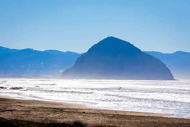Volcanic Morro Rock rises above coastal waters within protected natural preserve in Morro Bay California