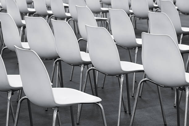 Lots of white plastic chairs lined up for an outdoor show.