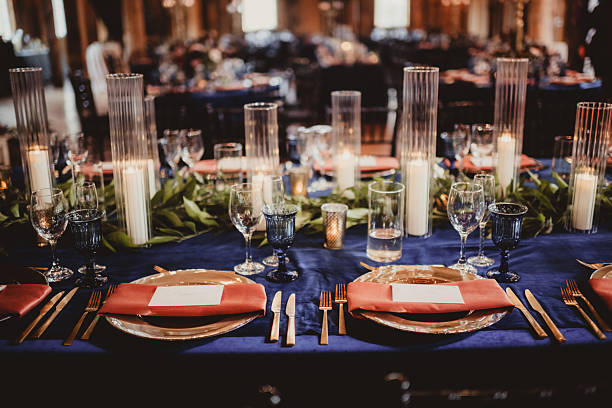 Wedding reception table setting with blue and orange with candles and greenery