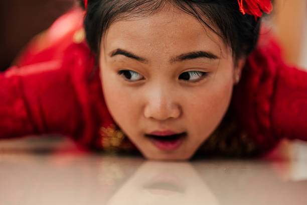 Close-up of a young Asian girl lying on the floor with a disappointed expression, showing emotional contrast during Chinese New Year at home