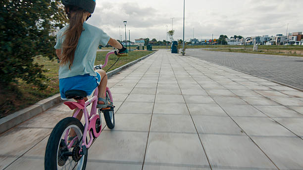 Elevated view of young girl riding bicycle on paved pathway, Florianopolis