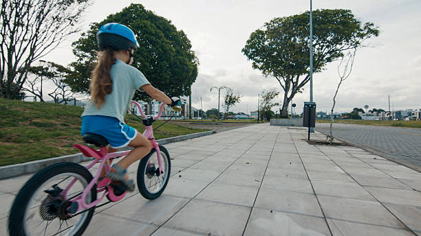 Elevated view of young girl riding bicycle on paved pathway, Florianopolis