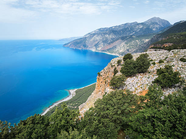 Gavdos island, Greece. Tripiti Beach. Rocky coastline with sparse vegetation and ocean waves, blue sky, summer sunny day